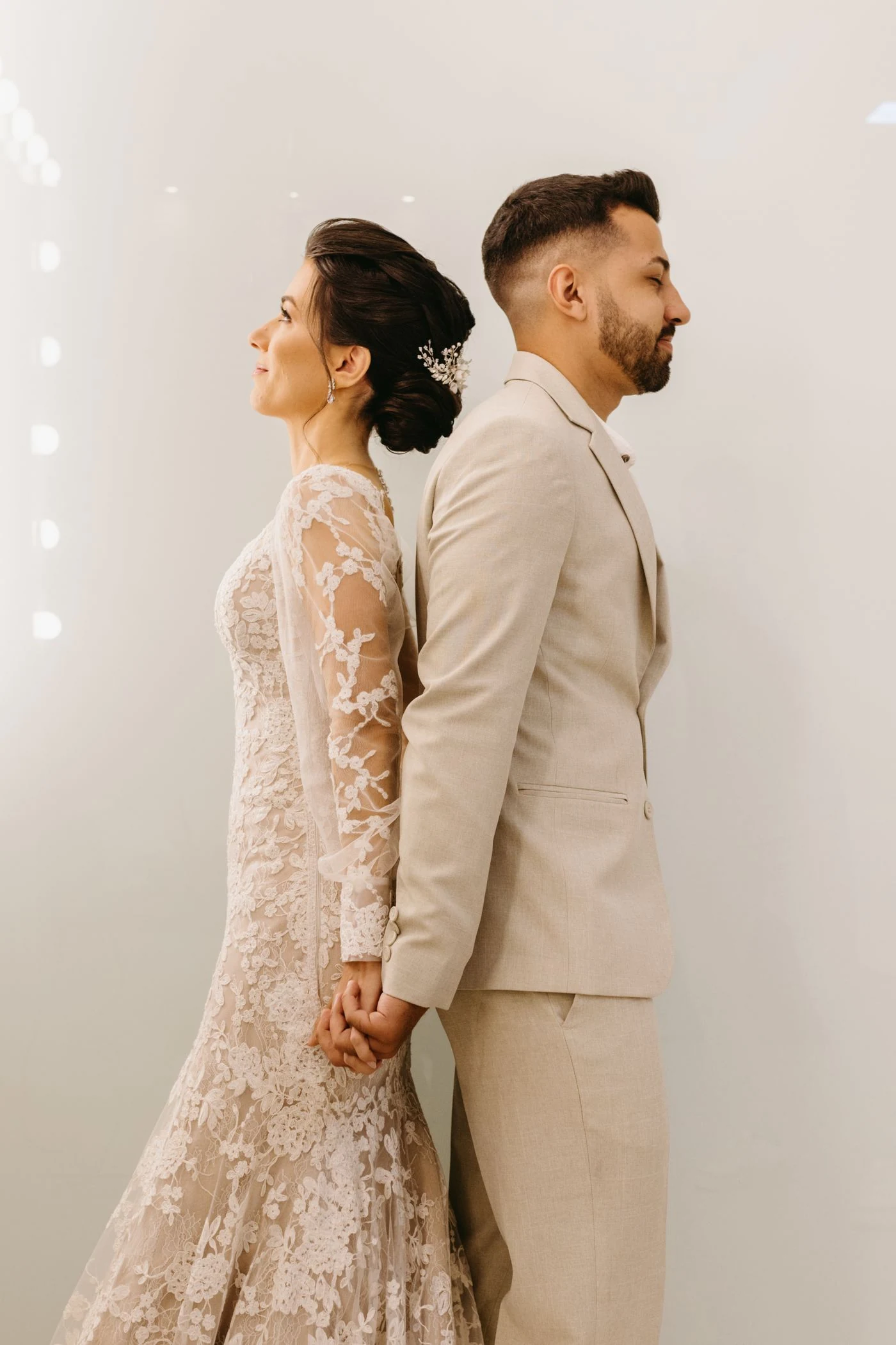 A stylish modern wedding couple in elegant neutral formalwear, photographed in a minimalist interior