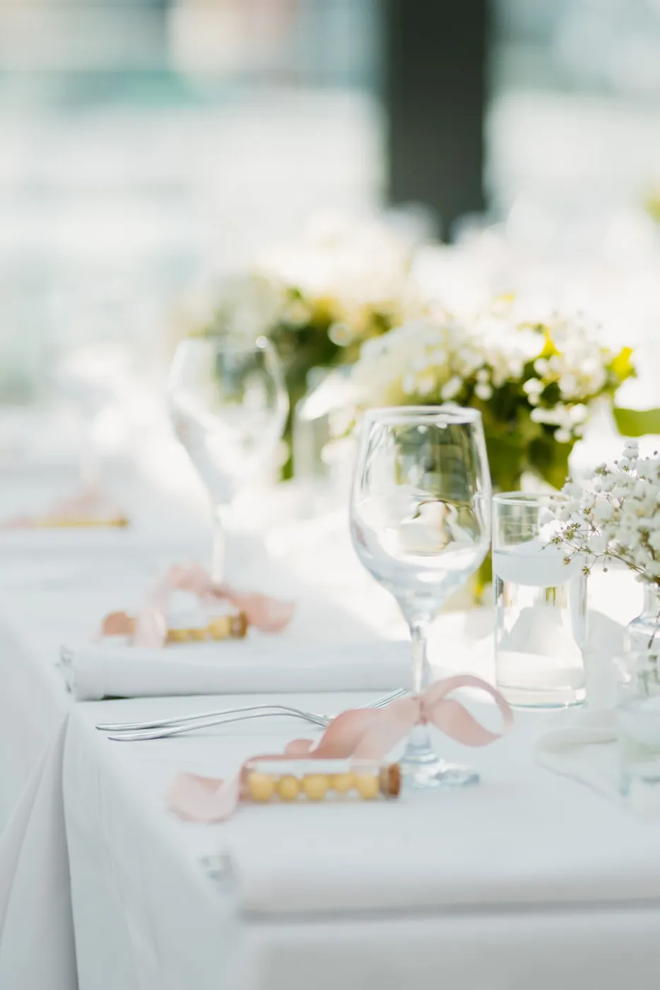 Beautifully arranged wedding reception table with floral centerpieces and glassware in a bright setting. Licensed inspiration image; not a BMG client portfolio claim.